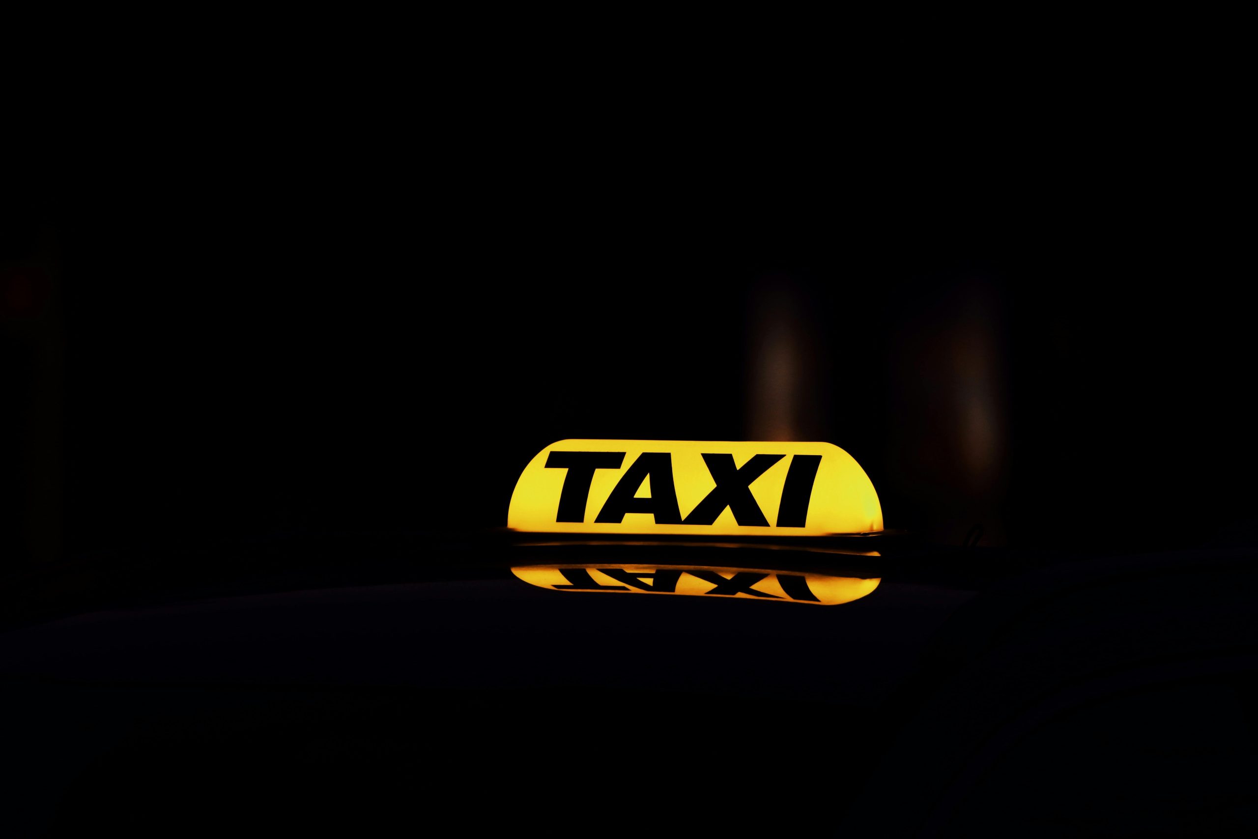 Yellow glowing taxi sign captured at night in Gothenburg, Sweden, highlighting urban city life.